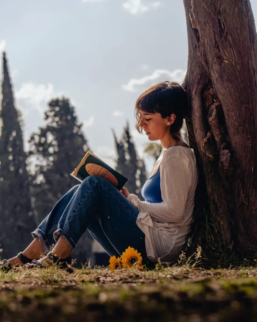 A woman reading Oscar Wilde beside a Tree