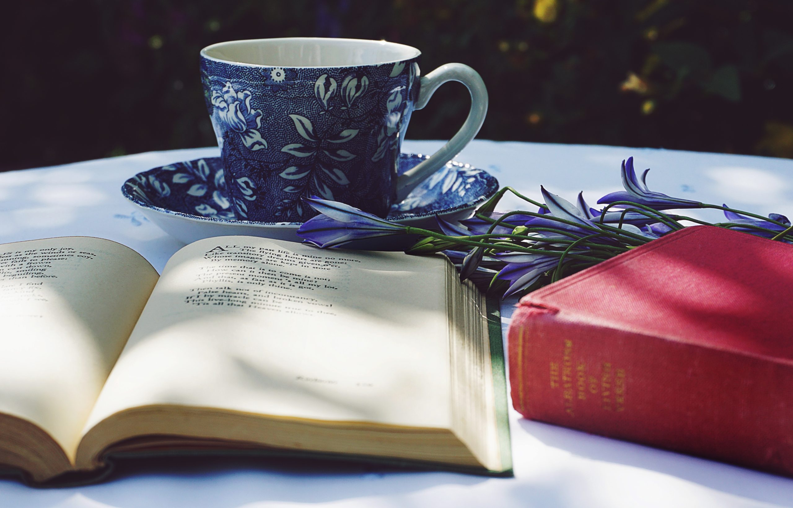 A book of poetry sitting on a table, along with a cup of tea in a beautiful china cup.