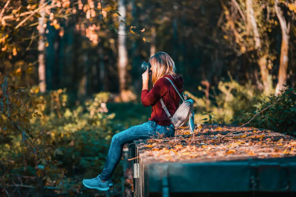 A woman sits outside basking in the beauty of fall, she is fully present in the moment.