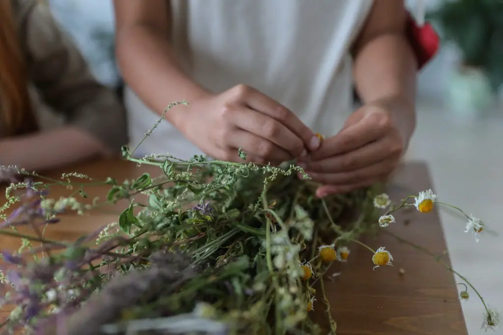 a woman is using twine to tie her wildflower bouquet.