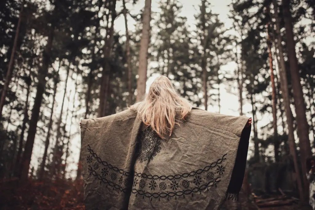 A woman spreads her arms, this is her way of forest bathing.