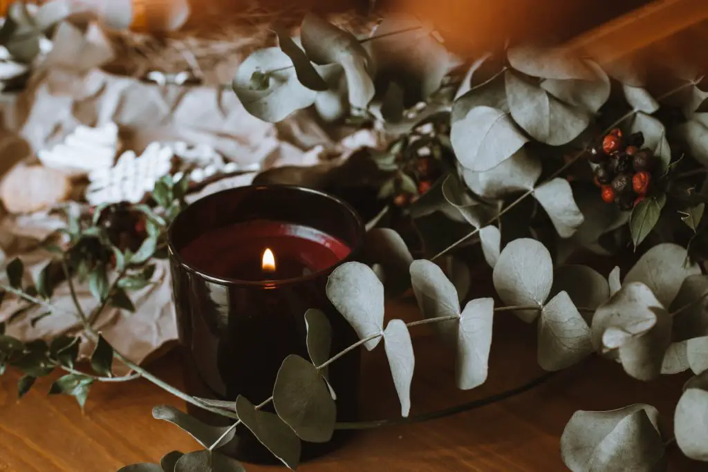 This photo shows an example of DIY decor items you could make: a beautiful rustic candle and a leaf garland.