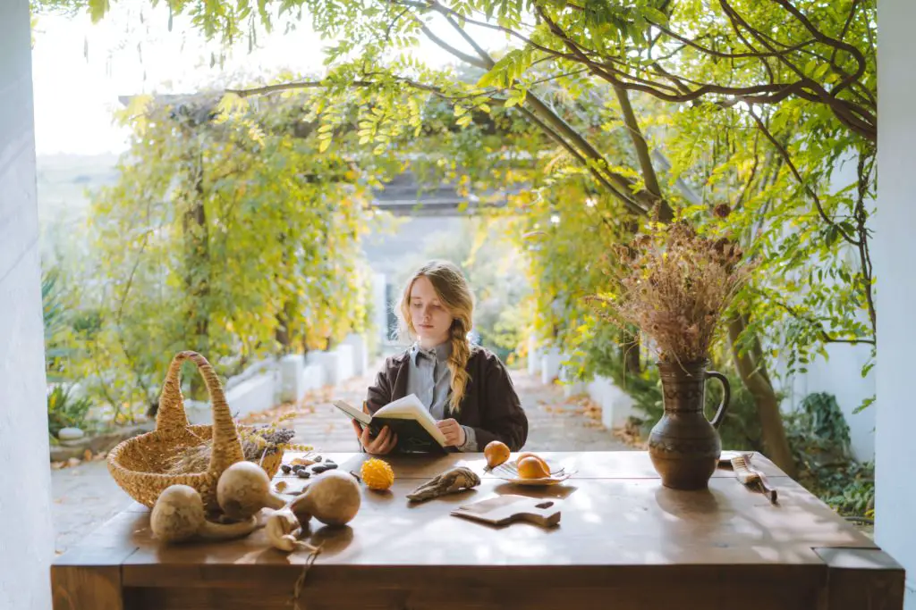 A woman sits outside at a table looking comfortable doing her daily reading